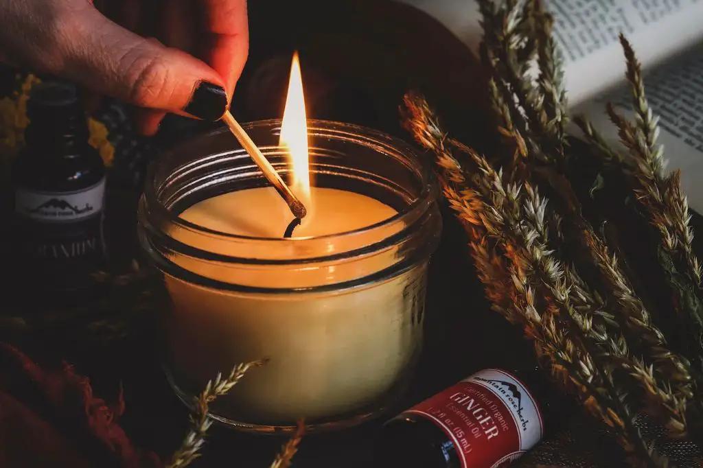 person lighting an aromatherapy candle containing essential oils.