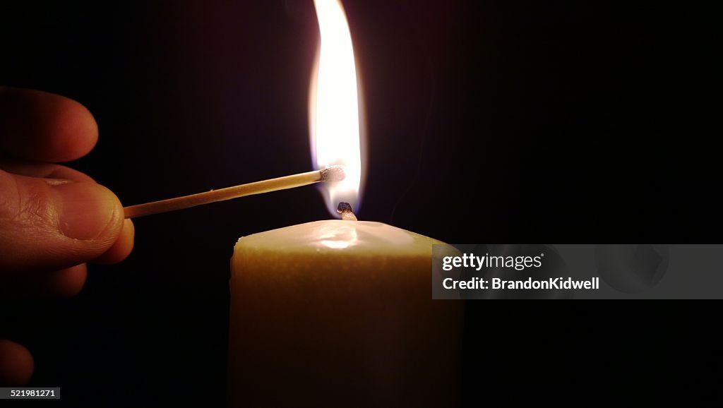 person lighting candle wick with match