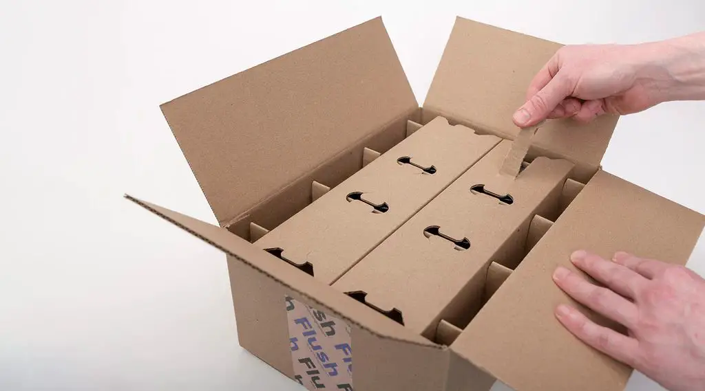 person packing candles for shipping using bubble wrap and gel packs