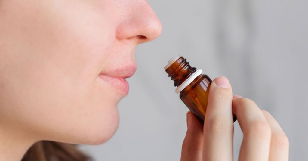 person smelling an essential oil bottle.