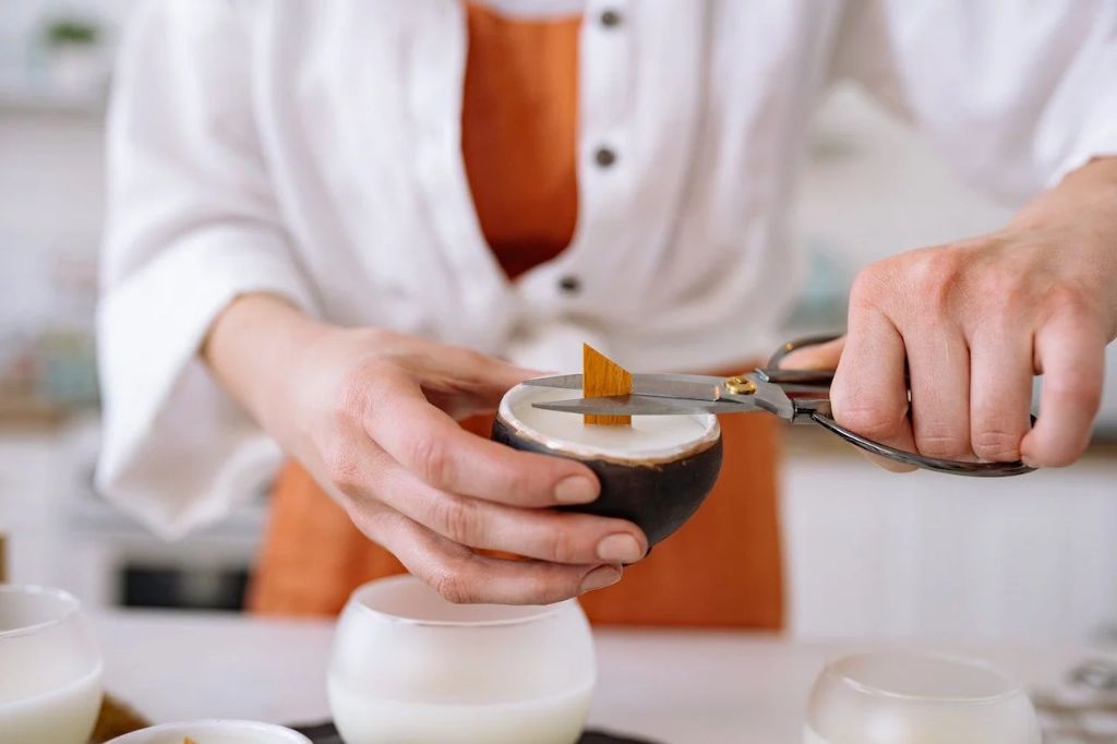 person trimming a candle wick with scissors