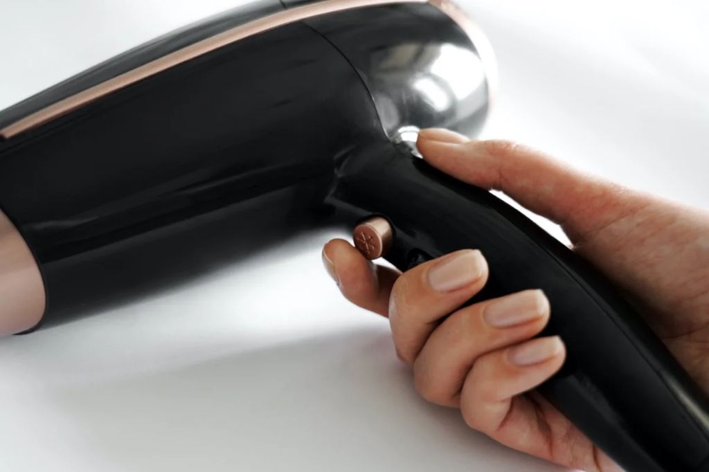 person using a hair dryer to remove wax from a glass jar