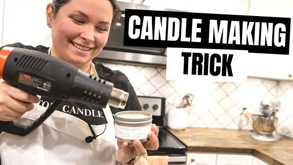 person using a heat gun to warm a glass jar before candle making