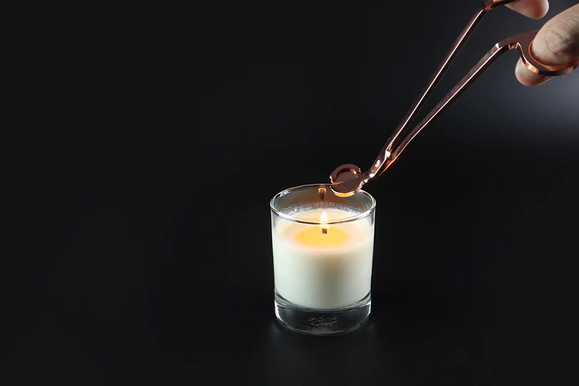 person using candle wick trimmers to cut a new candle wick before lighting