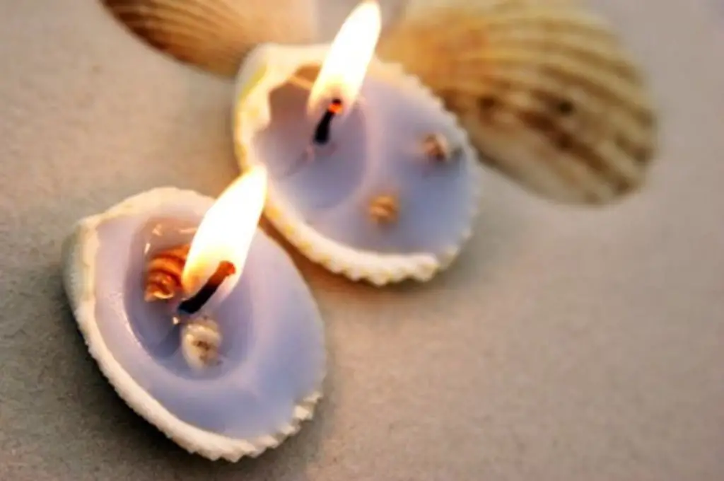 person washing a seashell under running water to prepare it for candle making