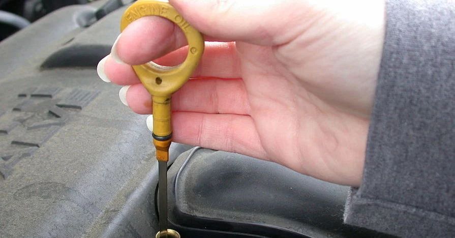 photo of an oil dipstick covered in black, smelly oil sludge buildup.