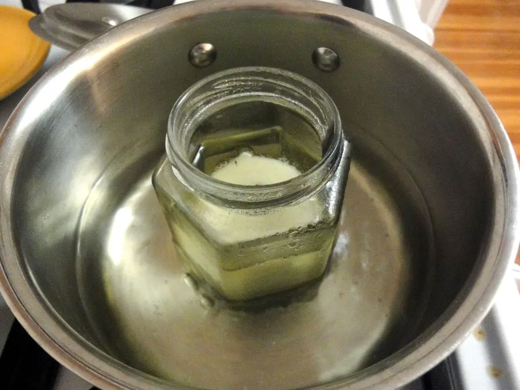 pouring hot wax into a glass container.