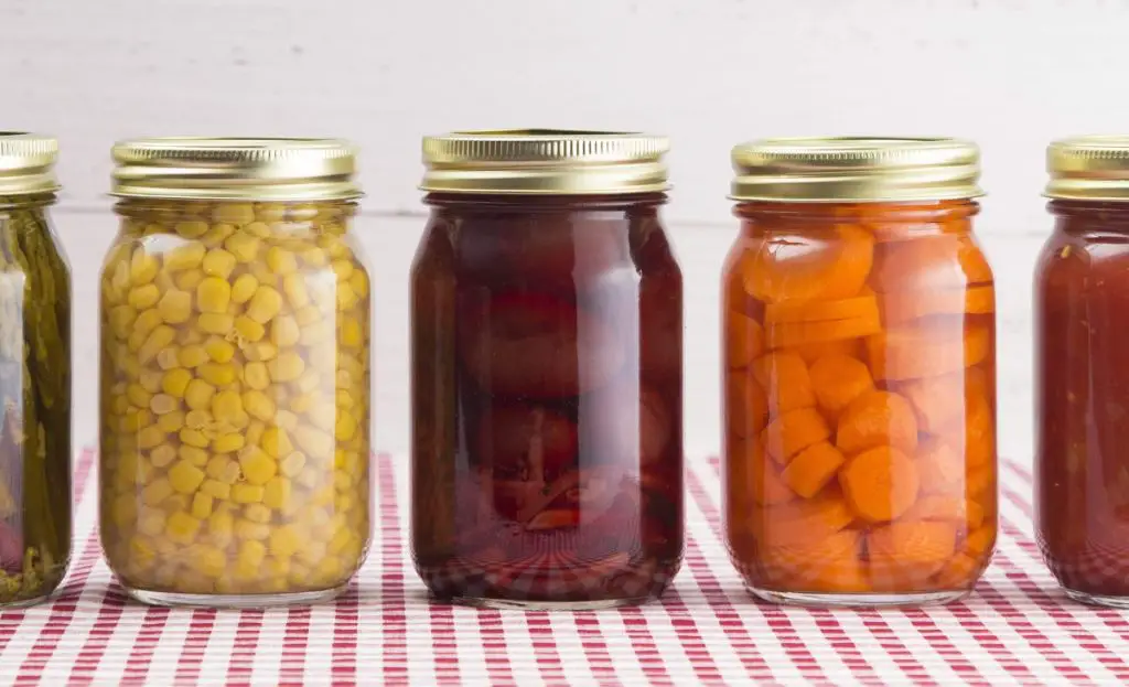 quart sized mason jars filled with canned fruits and vegetables.