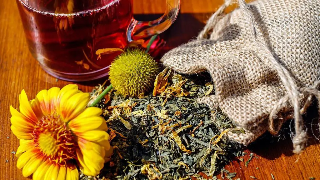 sage leaves with flowers and berries sitting in a wooden bowl, representing an herbal fragrance that could be used for candles