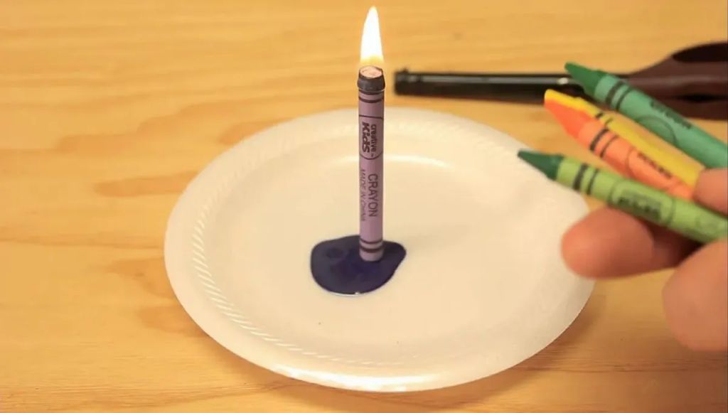 someone holding a crayon over a lit candle