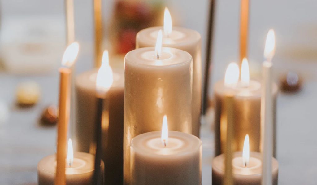 two lit wicks side by side in a white candle burning in a glass jar.