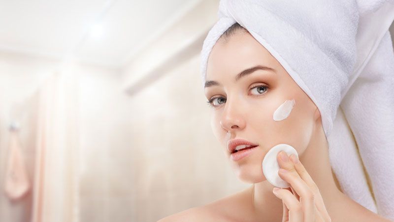 woman applying diluted grapefruit oil to face with cotton pad