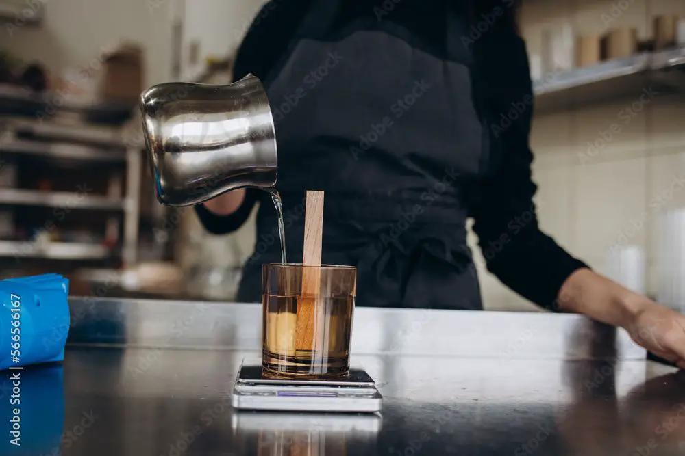 woman pouring soy wax into a glass container