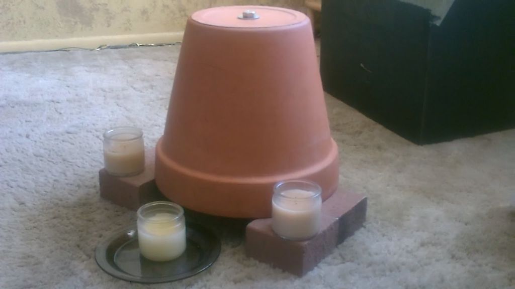 a makeshift heater made from terra cotta pots and candles emitting warmth.