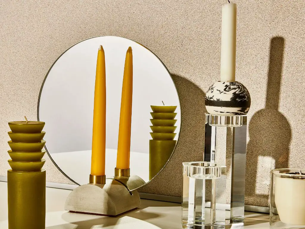 a person lighting a candle in a rotary candle holder on a table