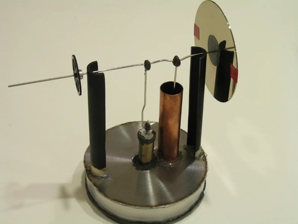 diagram showing heat from a candle flame being conducted into metal piston components in a candle engine