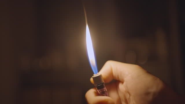 hand holding a classic metal lighter, igniting the flame.