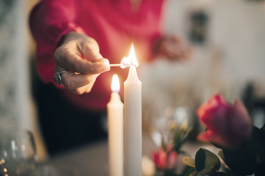 person carefully lighting a candle with a match