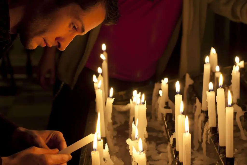 person lighting a candle and preparing for prayer