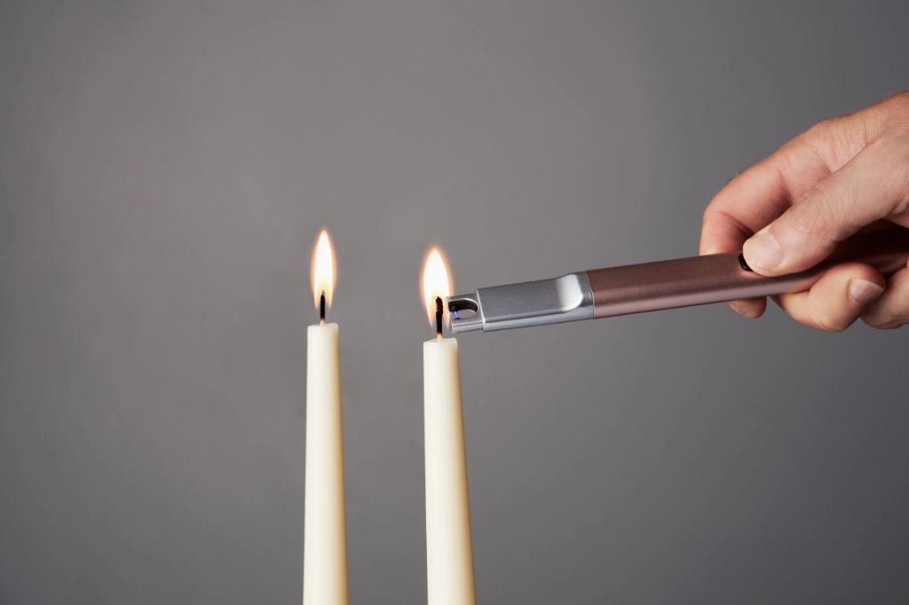 person using rechargeable candle lighter to light a candle